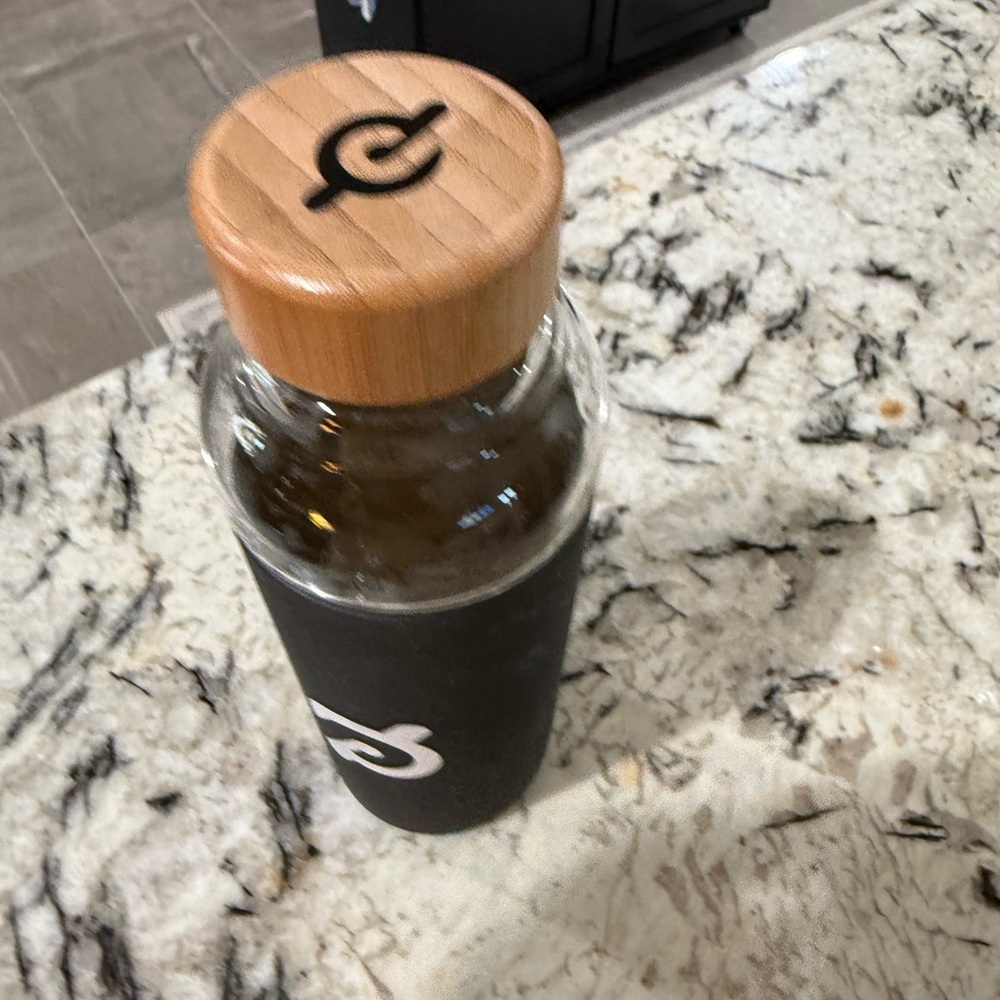 Peloton Studios Glass Water Bottle with Black Sleeve and Wooden Lid